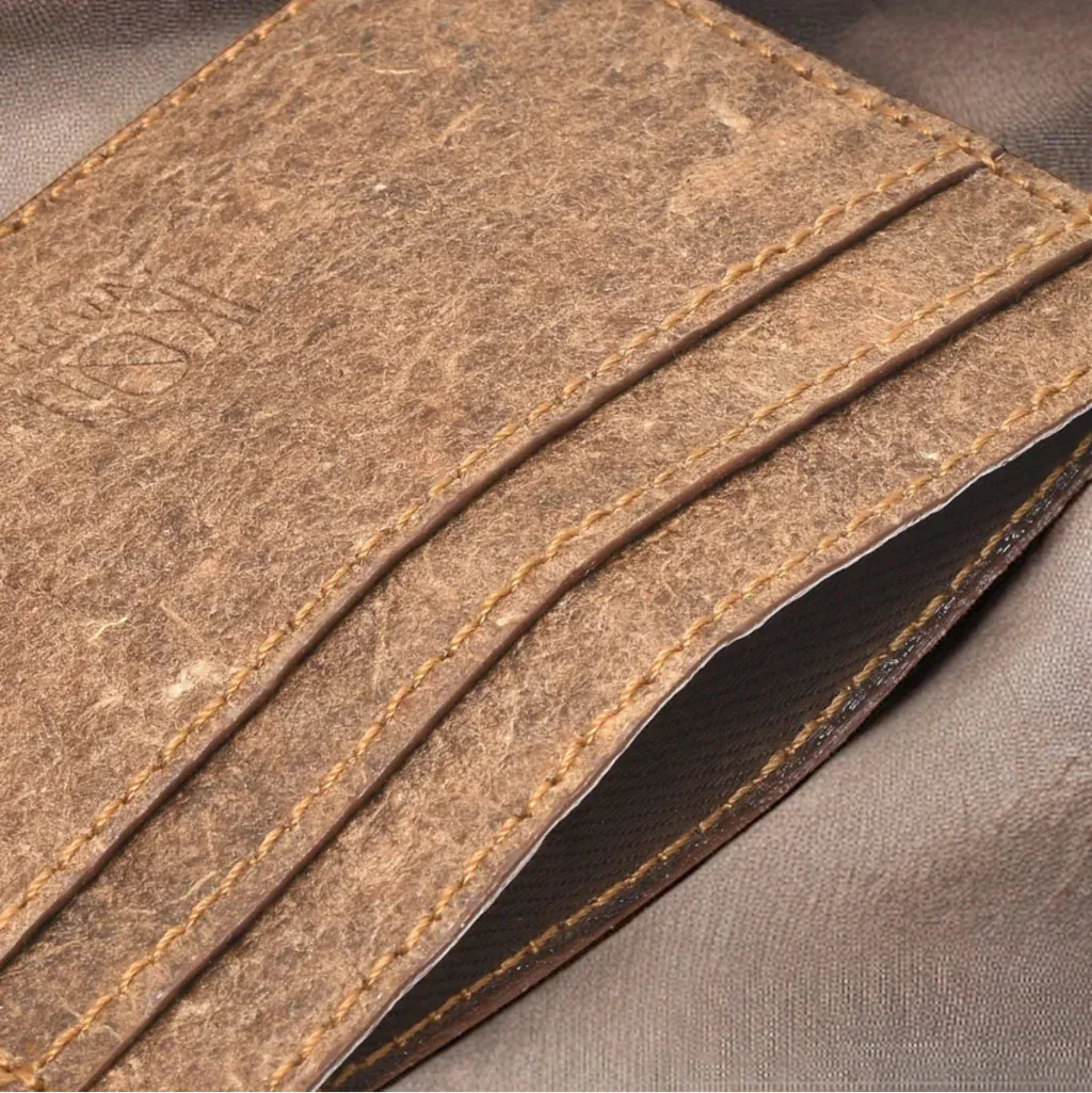 Gros plan du porte-cartes slim IKON Sweden en cuir végétal de noix de coco, finition marron naturelle avec coutures apparentes et texture artisanale.