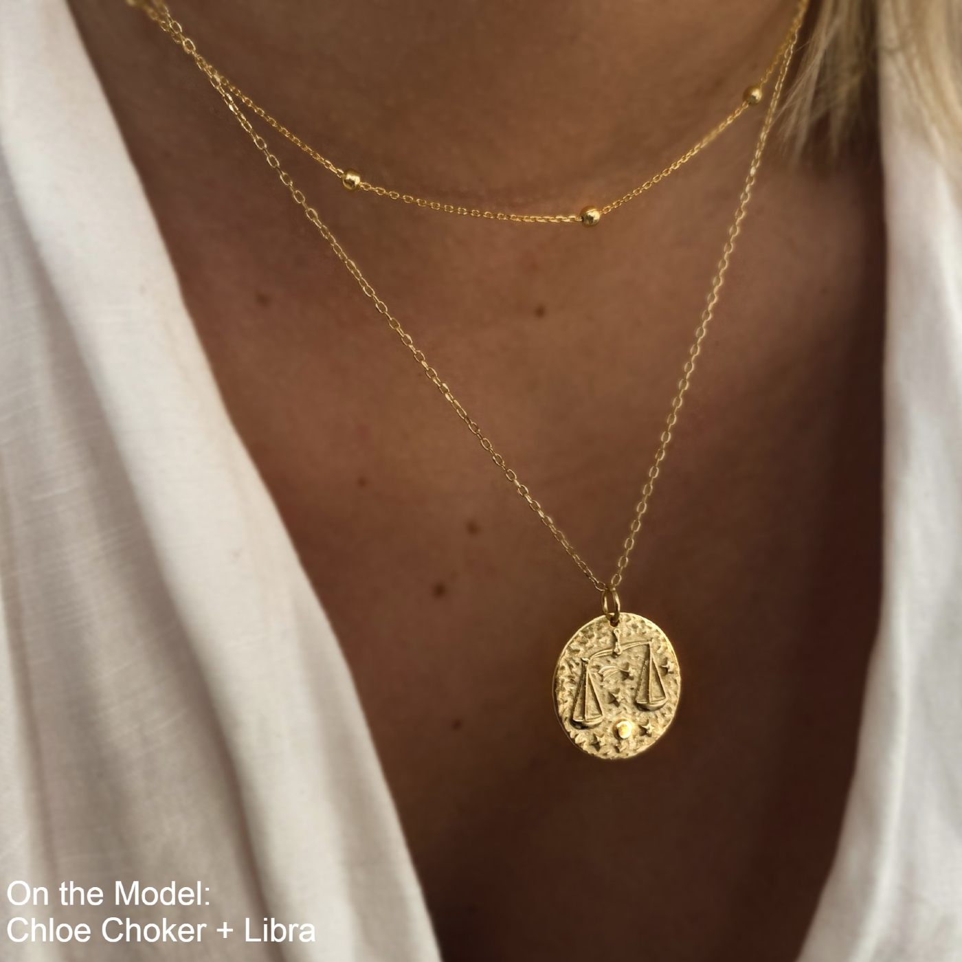 Collier Balance en plaqué or 18 carats avec pendentif rond gravé du symbole Balance et étoiles, porté sur un cou féminin, bijou élégant et raffiné. Idée cadeau femme.