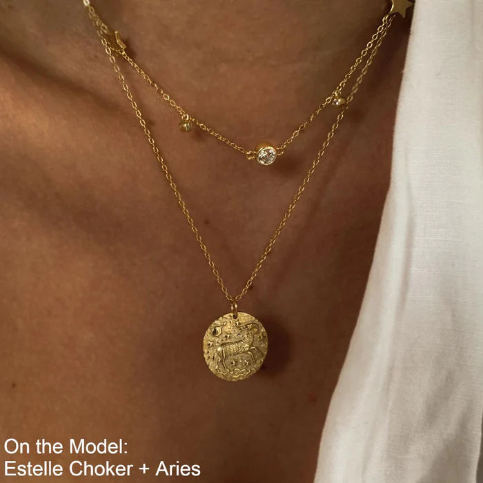 Collier Bélier doré porté en superposition avec un collier orné de zircons, sur une tenue blanche élégante. idée cadeau femme.