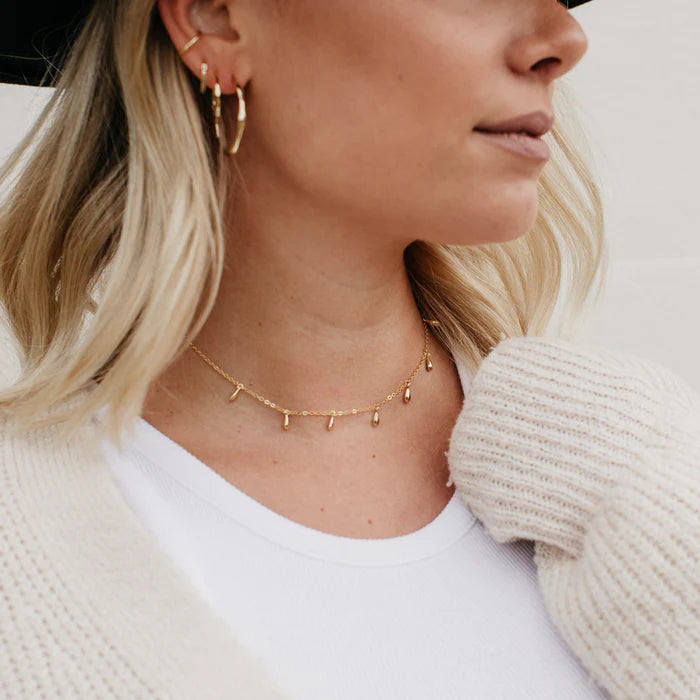 Femme portant le Lea Choker doré avec style bohÚme et cardigan. Idée cadeau femme. Koolkado.