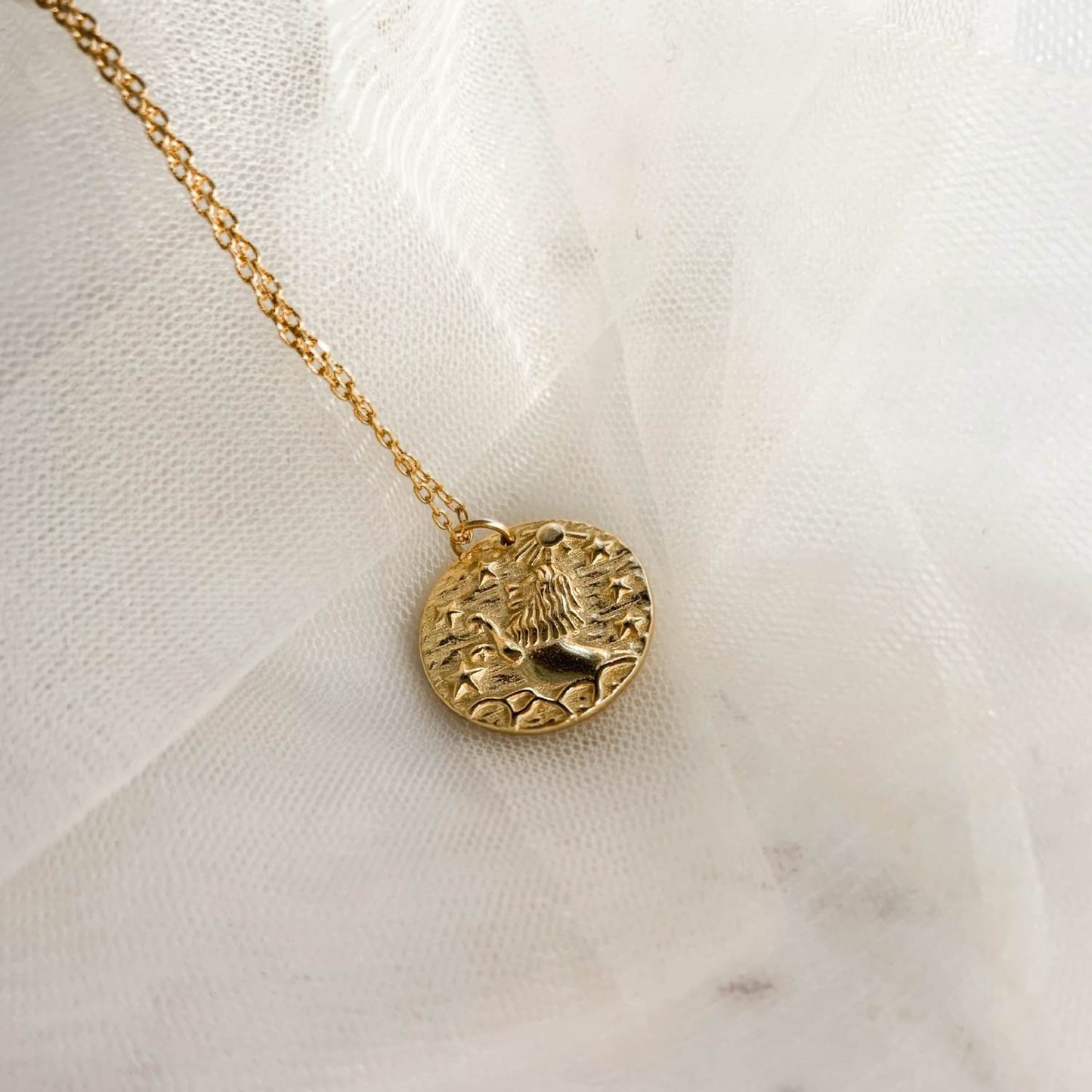 Collier en plaqué or 18 carats avec pendentif rond représentant un lion debout sous un soleil, sur fond texturé avec étoiles. Idée cadeau femme.