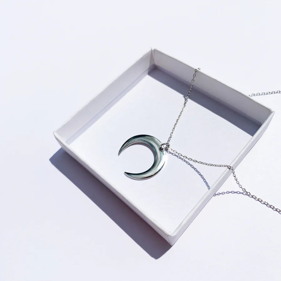 Collier lune argentée présenté dans un coffret blanc, prêt à offrir comme cadeau raffiné, idée cadeau femme.