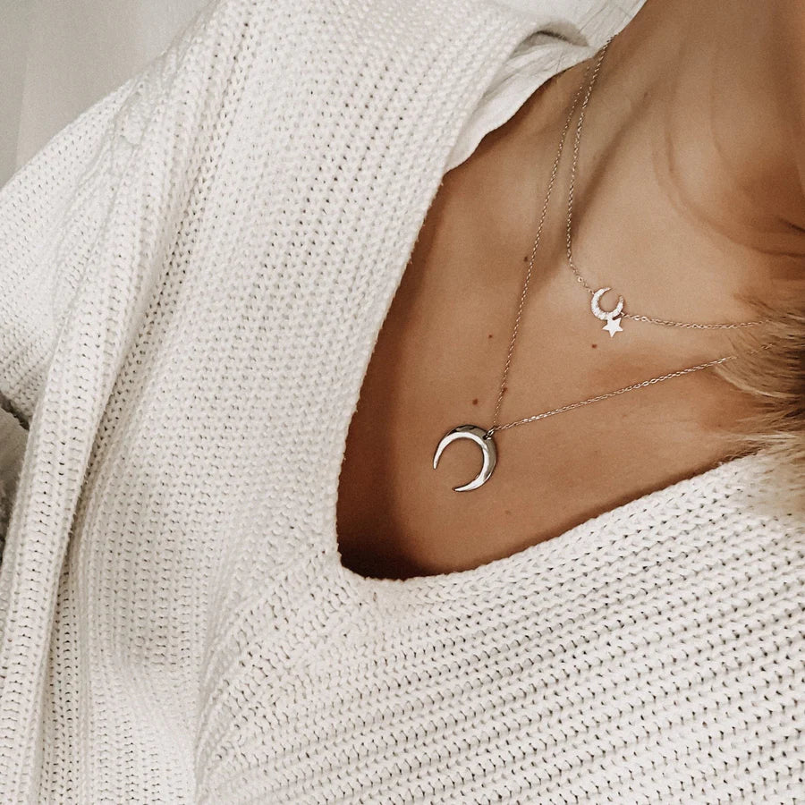 Femme portant un collier lune argentée en superposition, bijou discret et symbolique, idée cadeau femme.