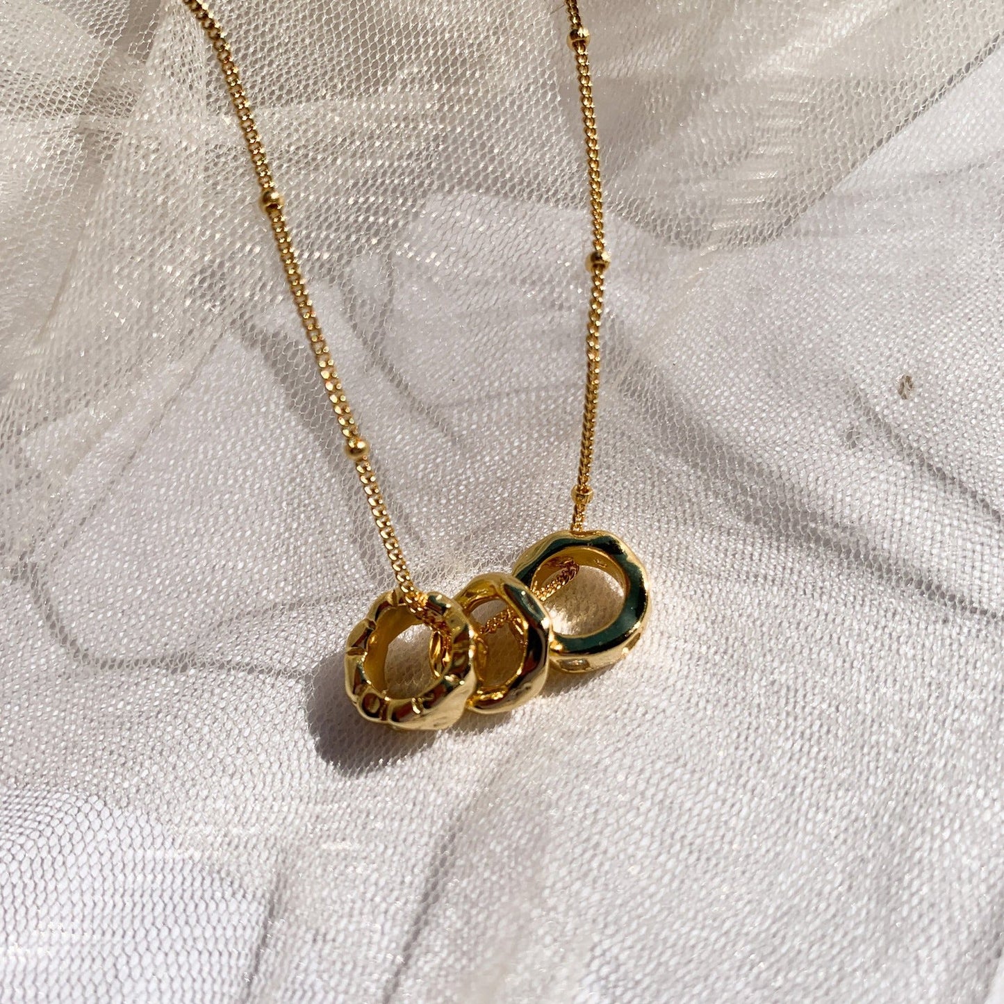 Collier Malou posé sur un tissu blanc transparent en lumière naturelle. Idée cadeau femme.