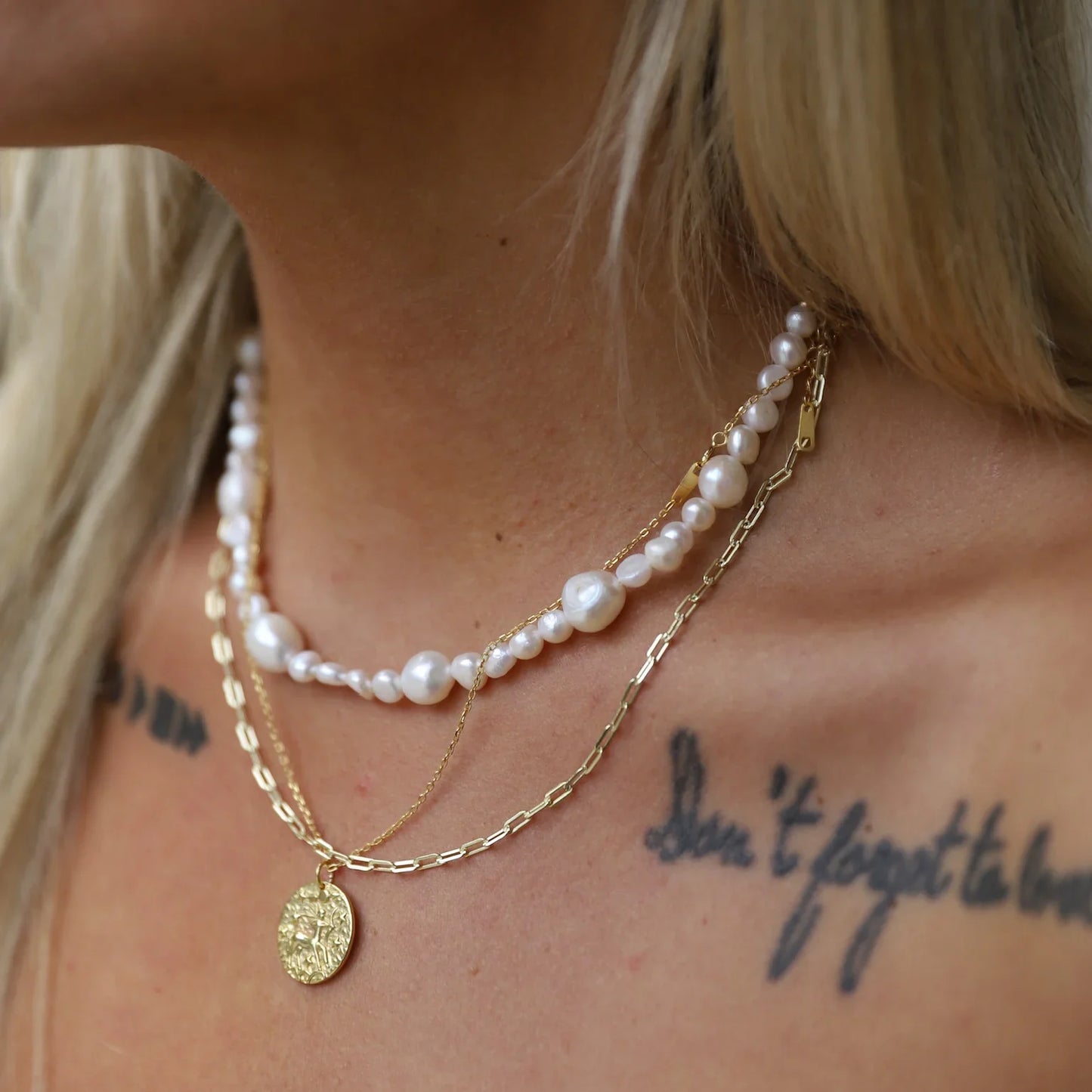 Collier sagittaire en plaqué or 18 carats avec double chaßne fine et collier de perles blanches porté par une femme, bijou élégant avec pendentif rond gravé du symbole Taureau. Idée cadeau femme