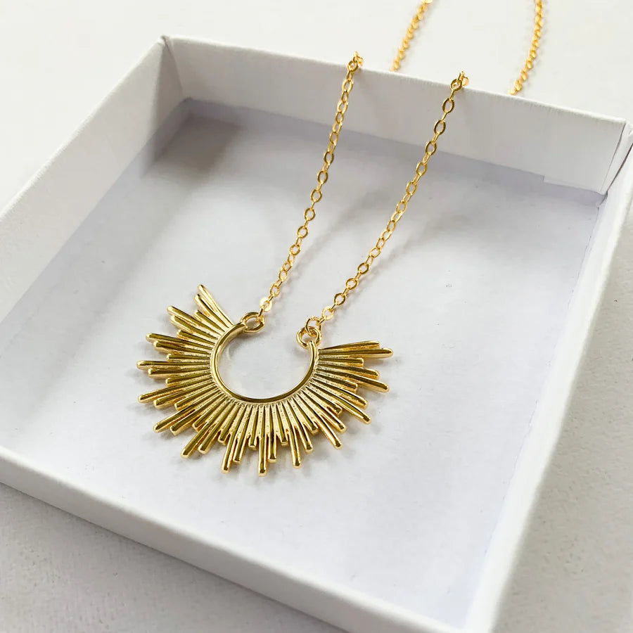 Gros plan du collier dorĂ© soleil dans son Ă©crin, prĂȘt Ă offrir en cadeau, idĂ©e cadeau femme.