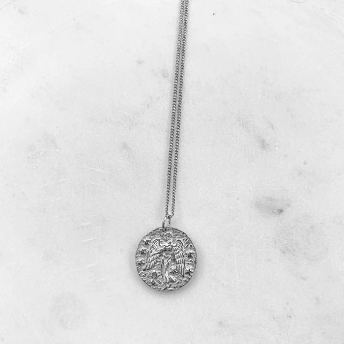 Collier Vierge argenté suspendu sur fond marbre clair, style minimaliste. Idée cadeau femme ou ado.