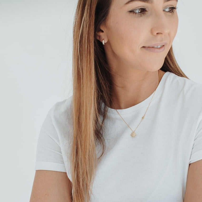 Idées cadeaux pour femme : collier double pendentif soleil porté avec un t-shirt blanc, bijou fin et lumineux parfait pour un look minimaliste et élégant