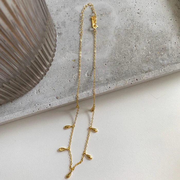 Choker doré Lea à pampilles sur fond béton clair. Idée cadeau femme. Koolkado.