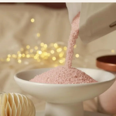 Versement de sable parfumé rose pour créer une bougie lors d’un rituel apaisant, geste créatif et élégant pour composer une ambiance douce à la maison – KoolKado