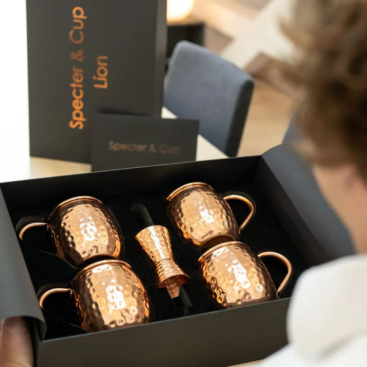 Vue de dessus du coffret Lion ouvert revelant les 4 mugs en cuivre et les accessoires de mixologie soigneusement ranges dans leur ecrin