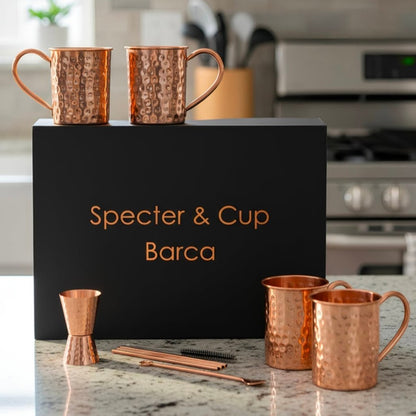 Set complet Moscow Mule Barca en cuivre pur martele avec 4 mugs pailles doseur et cuillere devant son coffret cadeau noir haut de gamme