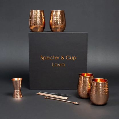 Set complet Moscow Mule Layla en cuivre pur martele avec 4 gobelets galbes pailles doseur et cuillere devant son coffret cadeau noir