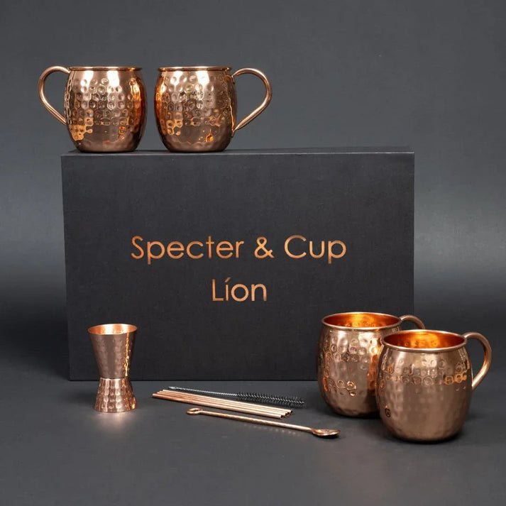 Set complet Moscow Mule Lion en cuivre pur martele avec 4 mugs pailles et doseur devant son coffret cadeau noir haut de gamme