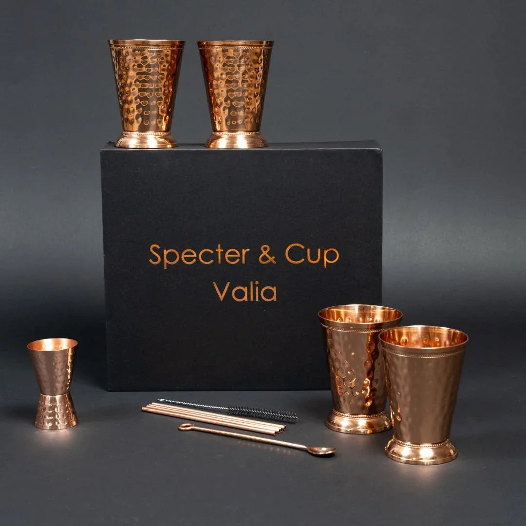 Set complet Moscow Mule Valia en cuivre pur avec 4 gobelets au relief romain pailles et doseur devant son coffret cadeau noir haut de gamme