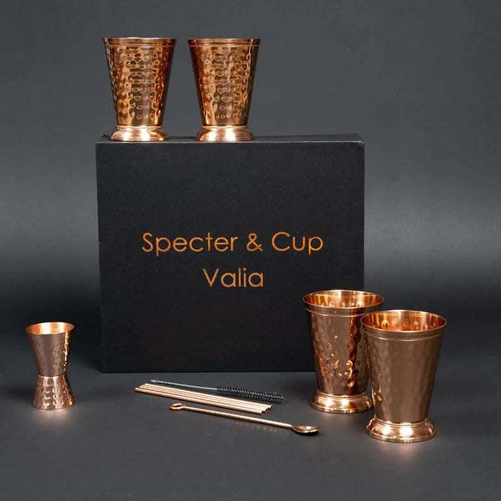 Set complet Moscow Mule Valia en cuivre pur avec 4 gobelets au relief romain pailles et doseur devant son coffret cadeau noir haut de gamme