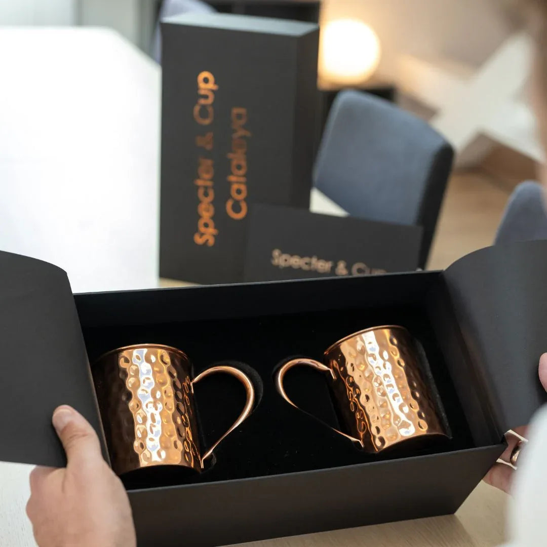 Coffret premium ouvert révélant deux mugs en cuivre martelé dans un écrin noir élégant, idée cadeau couple idéale pour une pendaison de crémaillère ou un anniversaire – KoolKado