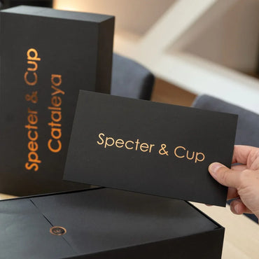 Mains ouvrant un coffret cadeau noir élégant contenant deux mugs en cuivre martelé, idée cadeau couple idéale pour une pendaison de crémaillère – KoolKado