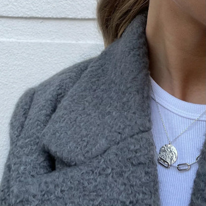 Collier vintage style carte ancienne porté avec un manteau en laine gris. collier atlas love local jewelry. Koolkado.