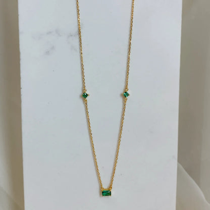 Collier doré avec pierre verte posé verticalement sur un fond marbré blanc. Idée cadeau femme, collier romy, koolkado.be