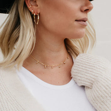 Femme portant le Lea Choker doré avec style bohème et cardigan. Idée cadeau femme. Koolkado.