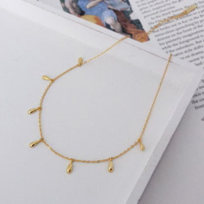 Collier Lea doré avec pampilles goutte photographié sur un livret. Idée cadeau femme. Koolkado.