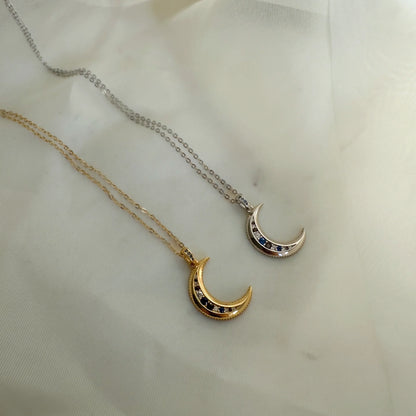 Deux colliers pendentif lune, version dorée et argentée, posés à plat sur tissu blanc. Idée cadeau femme.