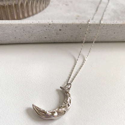 Collier Matea en argent posé sur une table claire, pendentif lune visible – Idées cadeau femme, collier Matea Love Local Jewelry, koolkado
