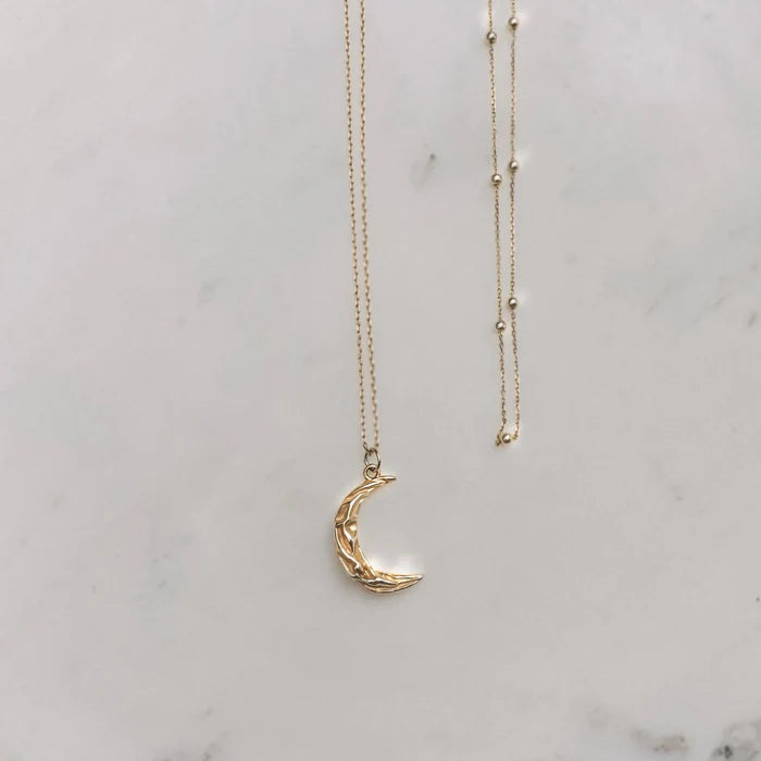 Collier Matea doré avec pendentif croissant de lune posé sur fond marbre – Idées cadeau femme, collier Matea Love Local Jewelry, koolkado