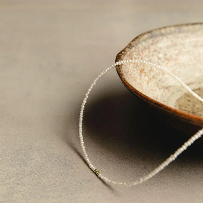 Idées cadeaux collier perles et doré présenté en mise en scène élégante, parfait pour femme