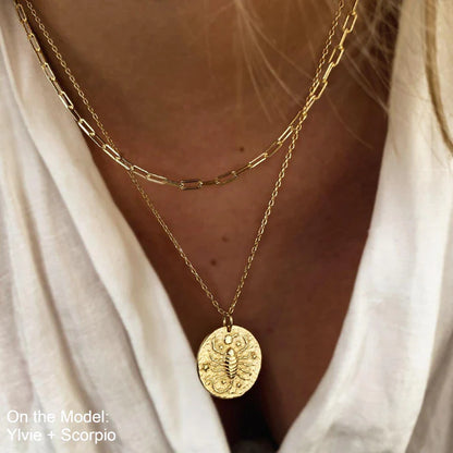 Collier Scorpion en plaqué or 18 carats porté en double chaîne par une femme, pendentif rond gravé d’un scorpion entouré d’étoiles, look tendance et élégant avec superposition de bijoux. Idée cadeau femme.