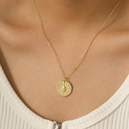 Collier Scorpion en plaqué or 18 carats porté par une femme, pendentif rond texturé gravé d’un scorpion, chaîne fine élégante, bijou féminin raffiné porté sur peau claire. Idée cadeau femme.