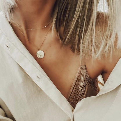Femme portant un collier Vierge doré avec chemise ouverte et top dentelle. Idée cadeau femme ou ado.