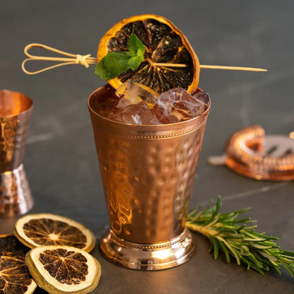 Gobelet en cuivre pur martelé en situation cocktail avec agrume séché et romarin, ambiance bar élégante – idée cadeau prête à offrir – KoolKado
