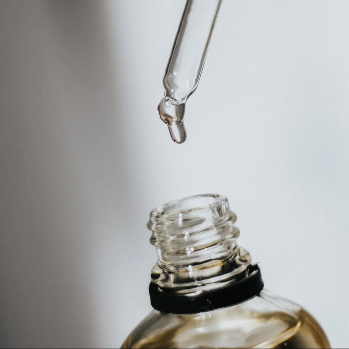 Ajout de quelques gouttes d’huile parfumée d’intérieur dans une bougie, idée cadeau élégante pour accompagner les moments cosy – KoolKado