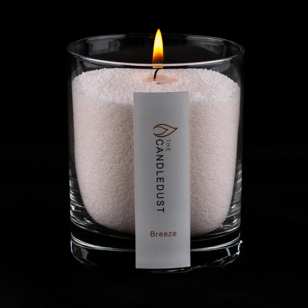 Idées cadeaux pour adulte : bougie parfumée Breeze Candledust allumée, mise en valeur sur fond sombre élégant