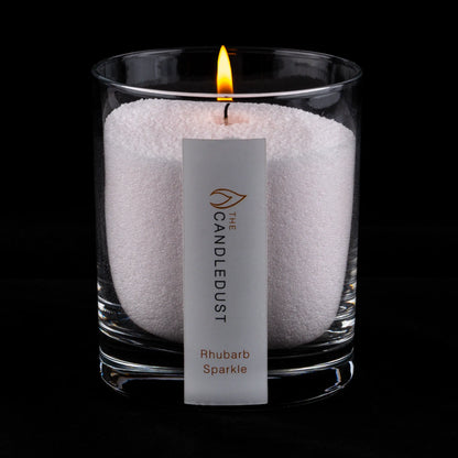 Idées cadeaux pour adulte : bougie parfumée Champagne & Rhubarbe Candledust allumée, mise en valeur sur fond sombre élégant