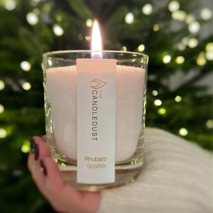 Idées cadeaux pour adulte : bougie parfumée Rhubarb Sparkle Candledust allumée, idéale à offrir pour une ambiance festive et chaleureuse en période de fêtes