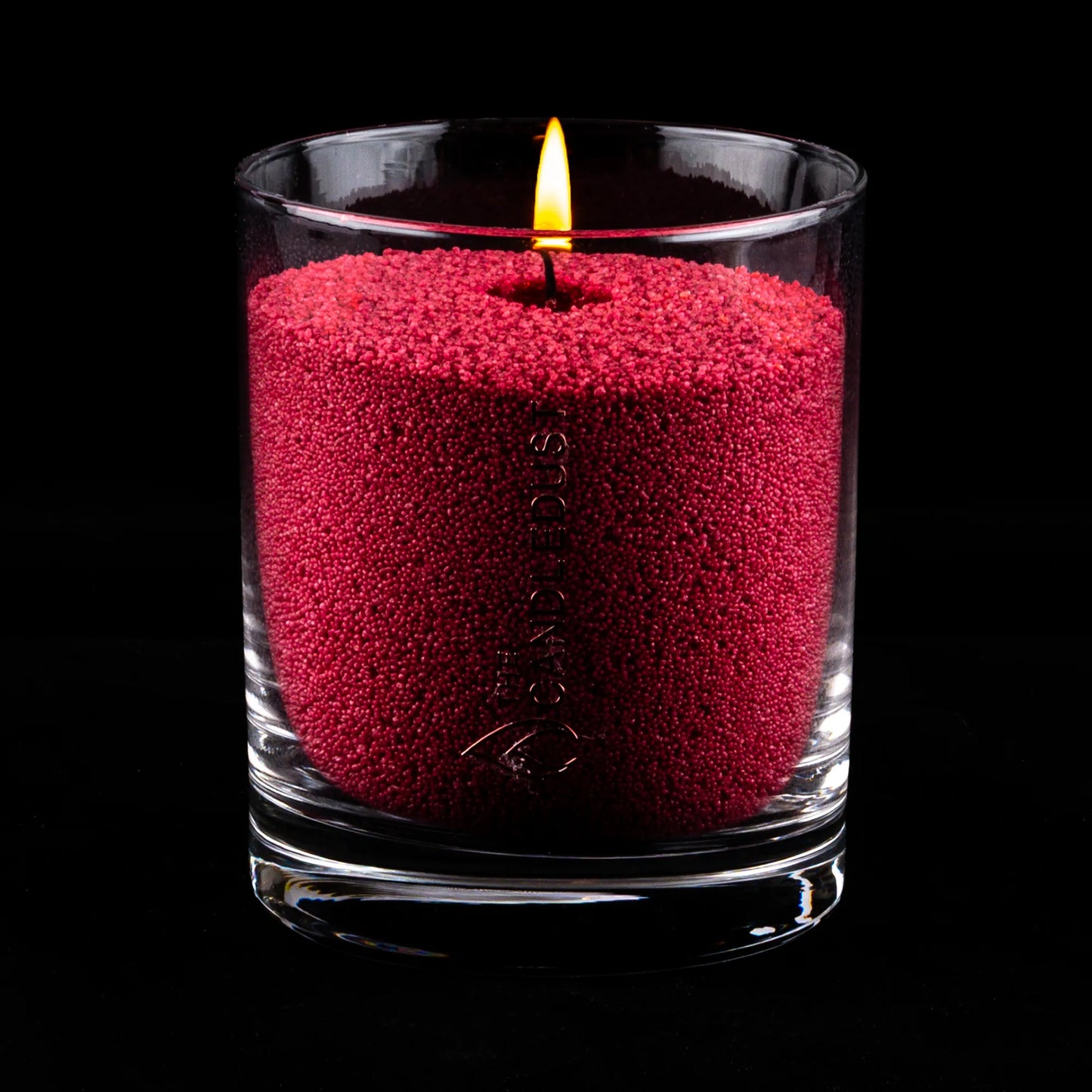 Idées cadeaux pour adulte : bougie parfumée Rosso Candledust allumée, mise en valeur sur fond sombre pour souligner son caractère profond et élégant