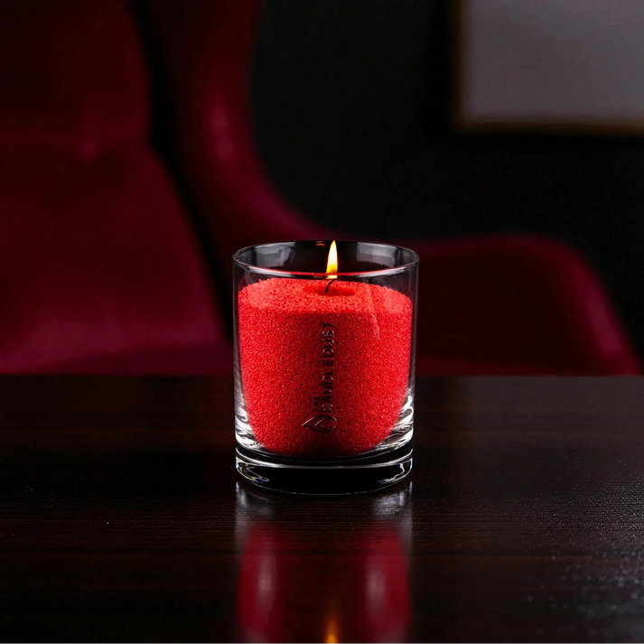 Idées cadeaux avec bougie en sable rouge créant une ambiance chaleureuse, idéale pour offrir un moment élégant et intime.