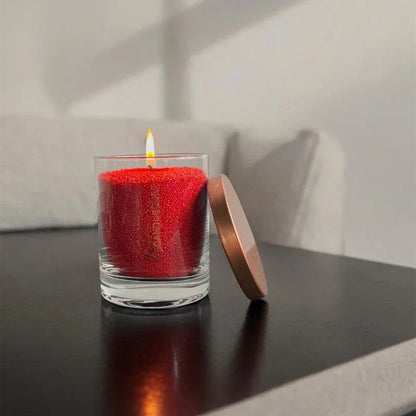Idées cadeaux avec bougie en sable rouge diffusant une lumière douce, parfaite pour offrir une ambiance chaleureuse.