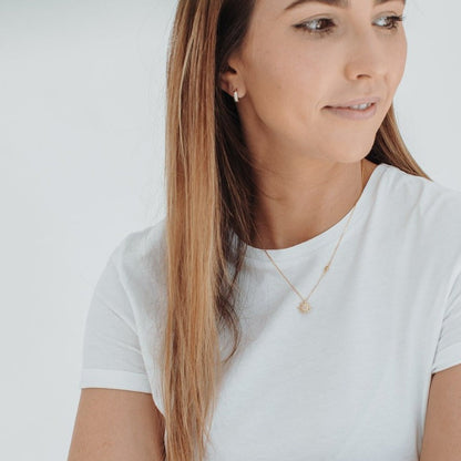 Idées cadeaux pour femme : collier double pendentif soleil porté avec un t-shirt blanc, bijou fin et lumineux parfait pour un look minimaliste et élégant