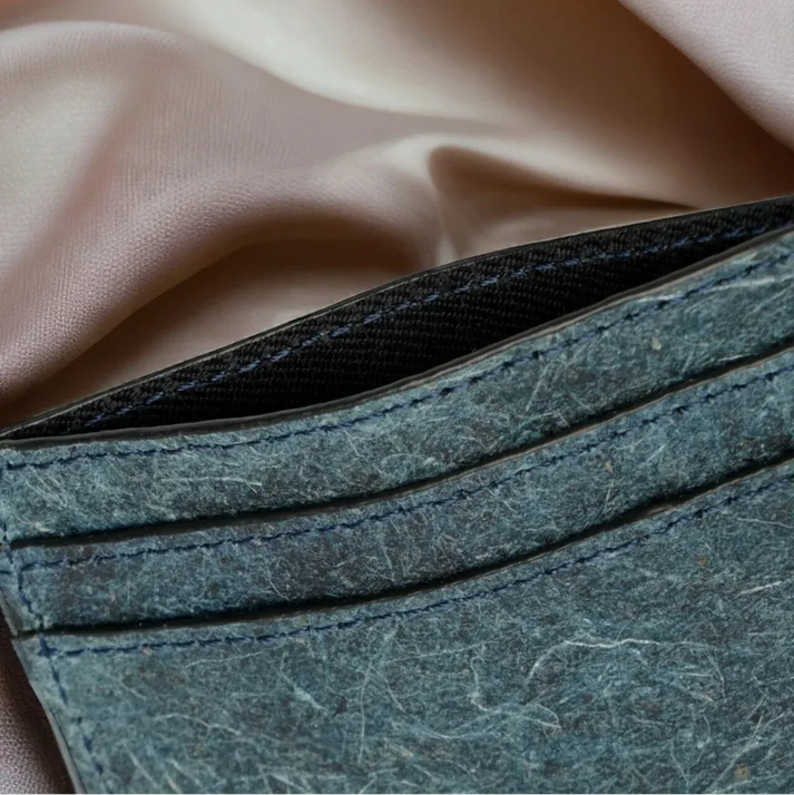 Gros plan des finitions d’un porte-cartes slim IKON Sweden bleu indigo en cuir végétal de noix de coco, coutures soignées et texture naturelle