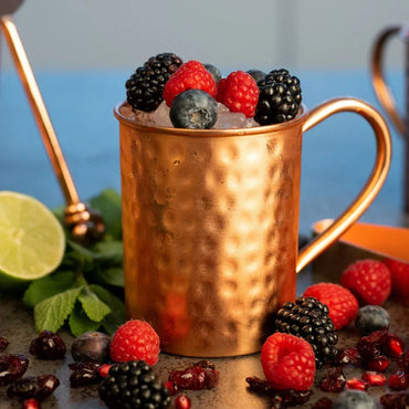 Mise en situation d un mug en cuivre Cataleya garni de baies et de glace pilee mettant en avant la fraicheur polaire du metal noble