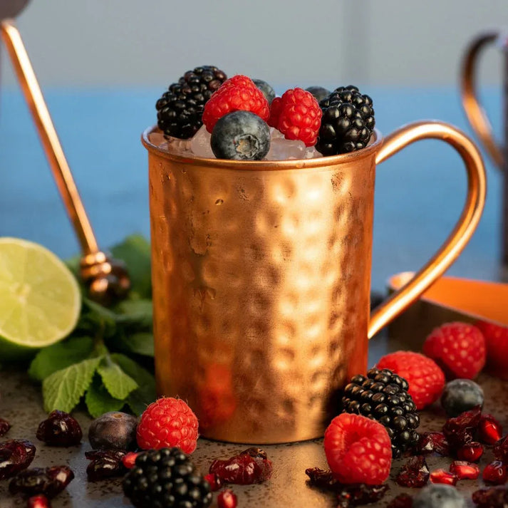 Mise en situation d un mug en cuivre Cataleya garni de baies et de glace pilee mettant en avant la fraicheur polaire du metal noble