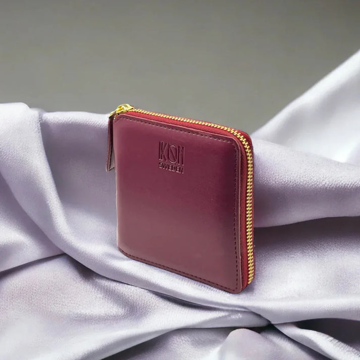 Porte-cartes zippé bordeaux en cuir végétal présenté dans une mise en situation élégante, format compact et raffiné, idée cadeau chic – KoolKado
