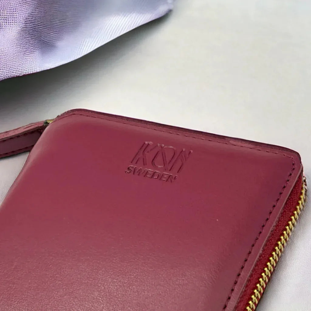 Détail du logo embossé sur un porte-cartes zippé bordeaux en cuir végétal, finition soignée et design élégant, idée cadeau responsable – KoolKado