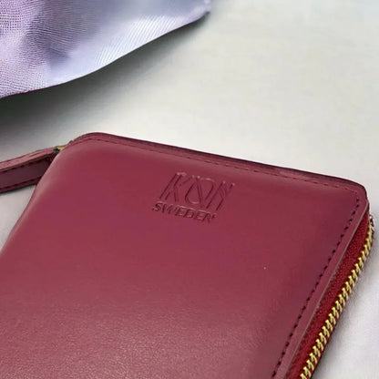 Détail du logo embossé sur un porte-cartes zippé bordeaux en cuir végétal, finition soignée et design élégant, idée cadeau responsable – KoolKado