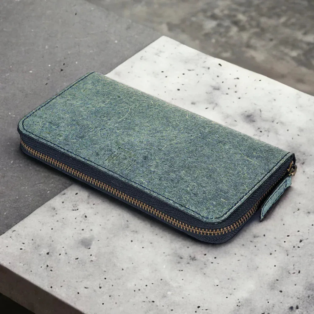 Portefeuille long zippé en cuir végétal vert posé sur une surface minérale, design élégant et contemporain, idée cadeau raffinée pour le quotidien – KoolKado